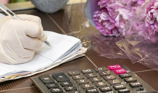 Gloved hand writing and flowers on desk