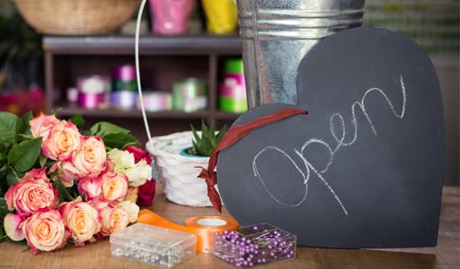 Open sign on shop counter with flowers