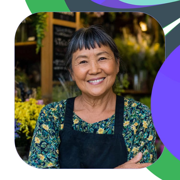 portrait of femail florist smiling in shop facing camera with iris, periwinkle and fern motif.