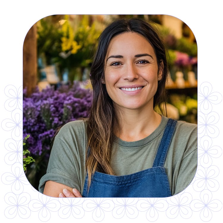 portrait of female florist smiling in shop facing camera with motif pattern background